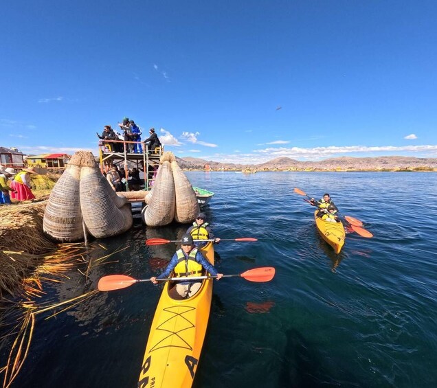 Kayakers on a calm lake, a traditional structure with conical roofs, and a distant mountain range. 1