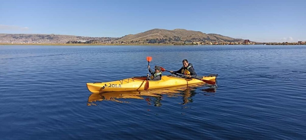Two people kayaking on calm water with a mountain in the background. 5