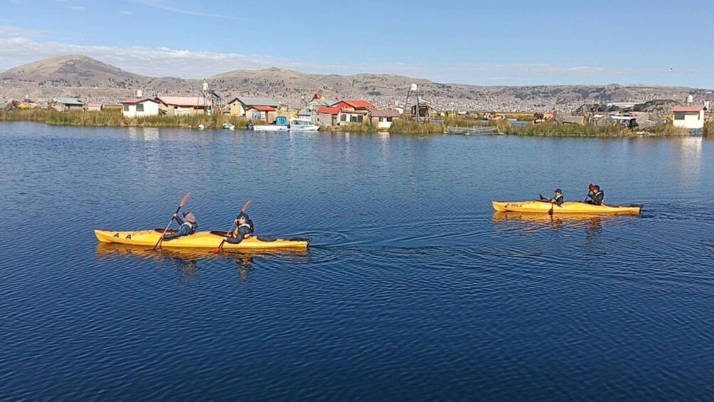 Two kayaks on a calm lake with a town in the background. 4