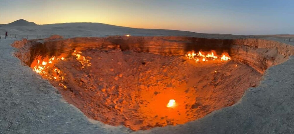 A large, deep pit with a fire burning at the bottom, surrounded by a flat, barren landscape. 5
