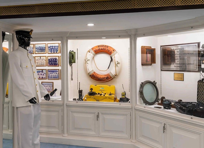A maritime exhibit with a lifebuoy, a shipbuilding engine, and a mannequin in a white uniform. 4