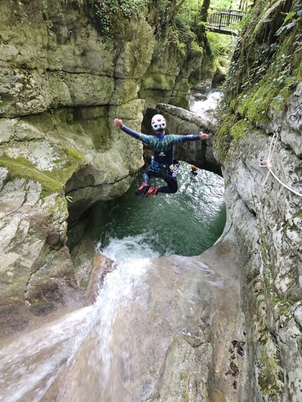 A person jumping into a water-filled crevice surrounded by moss-covered rocks. 1