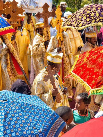 A group of people in ceremonial attire, some holding crosses and others carrying umbrellas. 2