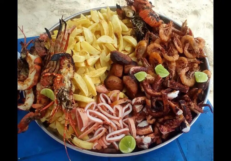 A seafood platter with various cooked seafood, including shrimp, squid, and octopus, accompanied by fries and lime wedges. 4