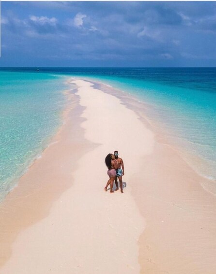 A couple embracing on a beach with clear turquoise water and a sandy shore. 5