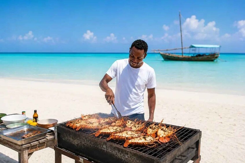 A person grilling seafood on a beach with a boat in the background. 1