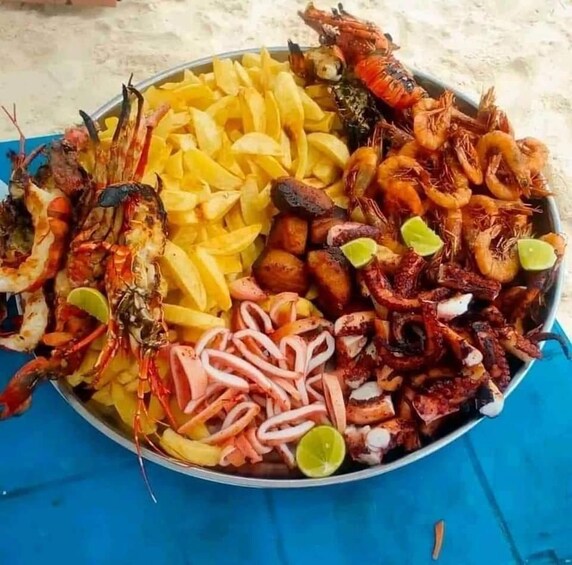 A seafood platter with various cooked seafood, including shrimp, squid, and lobster, served on a blue tablecloth. 2