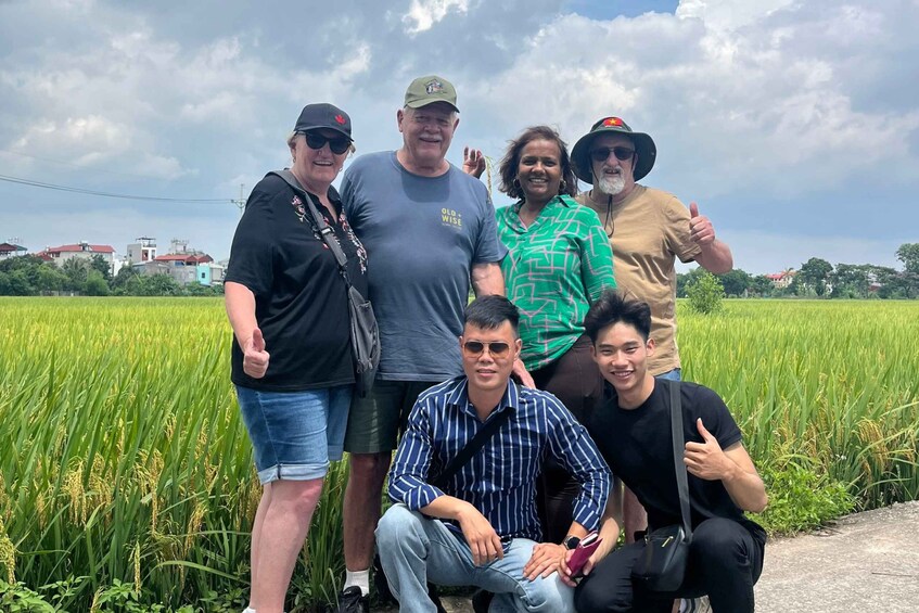 A group of people standing in a rice field with a cloudy sky in the background. 3