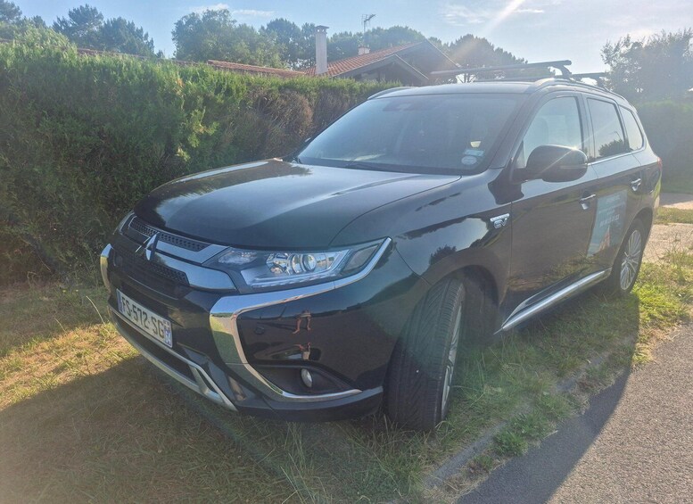 A black SUV parked on a grassy roadside with a clear sky and trees in the background. 5