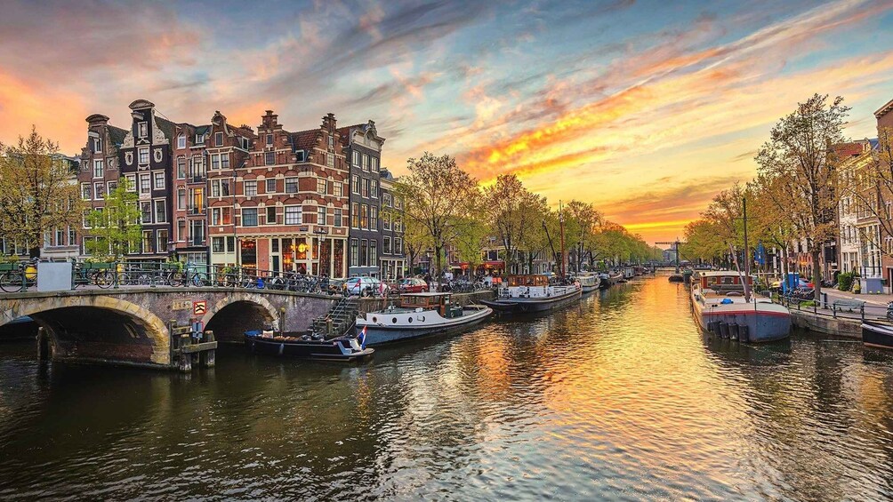 A canal with boats, a bridge, and historic buildings during sunset. 5