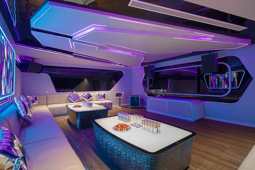 Ein modernes Interieur mit Neonbeleuchtung, einem weißen Sofa, einem Couchtisch mit Snacks und einem großen Bildschirm. 3