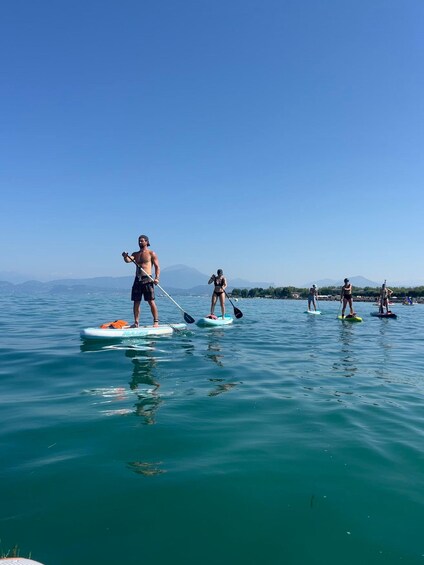 People paddleboarding on a calm sea with mountains in the background. 1