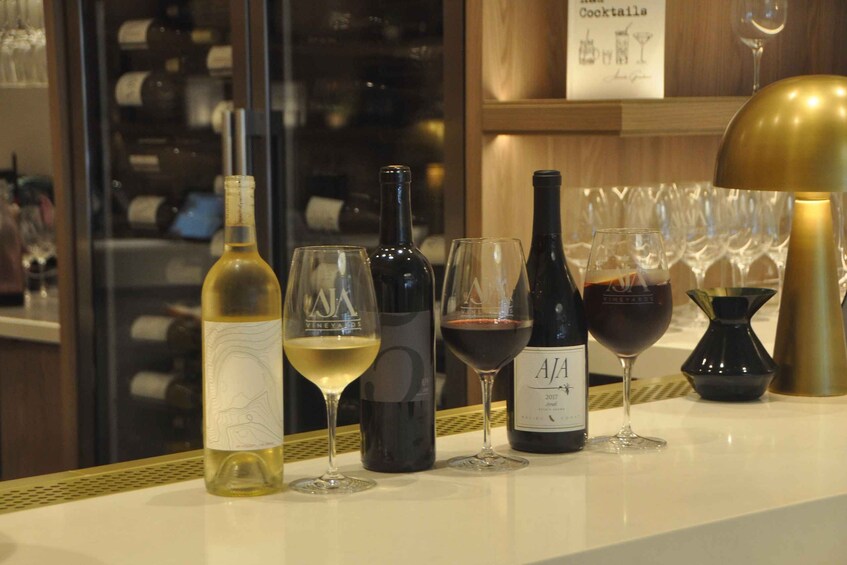 A wine tasting setup with various bottles and glasses on a counter. 3