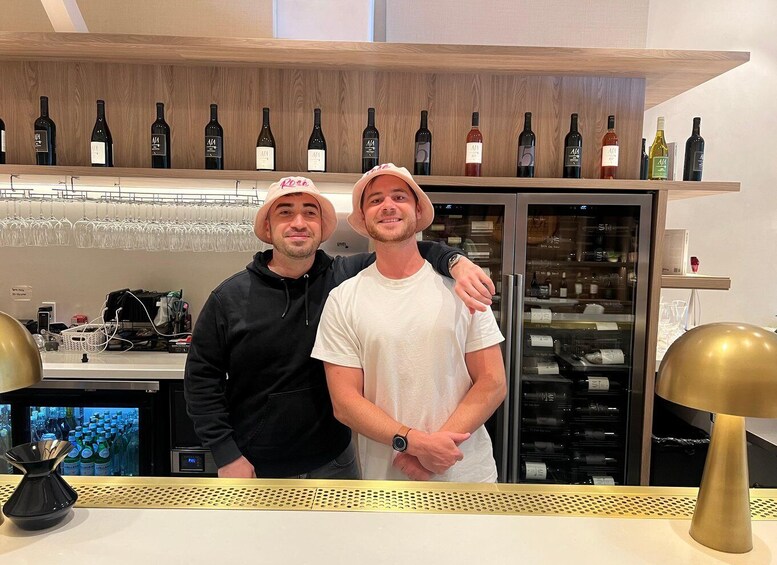 Two people standing in a bar with a wine rack in the background. 5