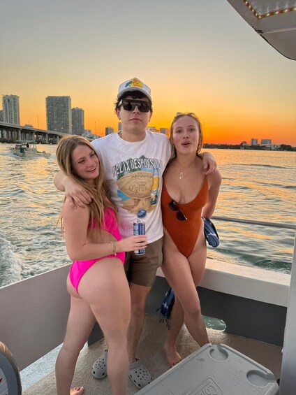 Three people on a boat with a city skyline and sunset in the background. 4