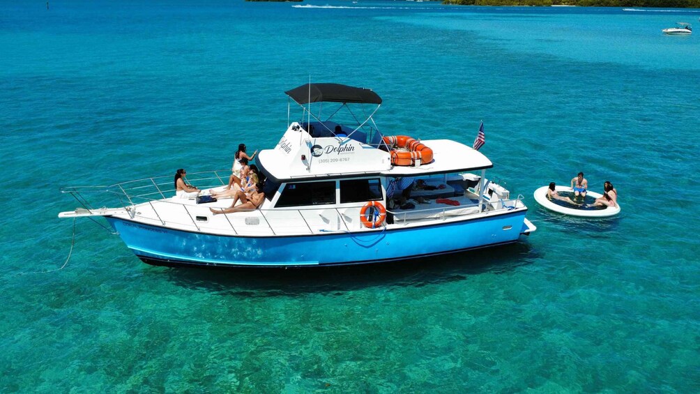 A blue boat with people on board, a lifebuoy, and a smaller inflatable boat nearby. 2
