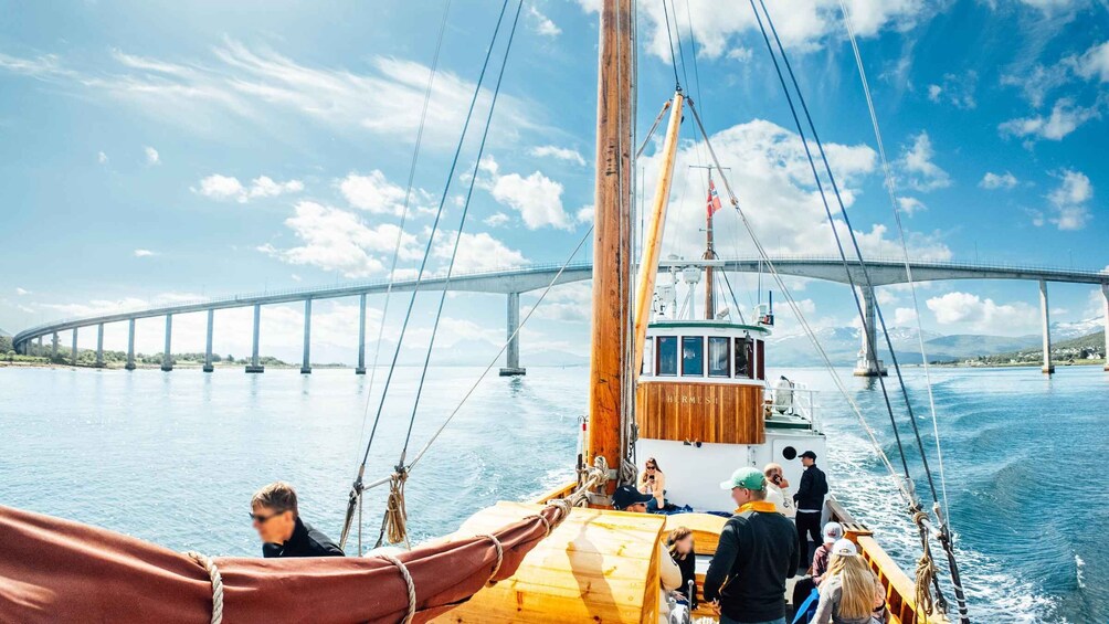 A boat with passengers, a wooden cabin, and a bridge in the background. 5