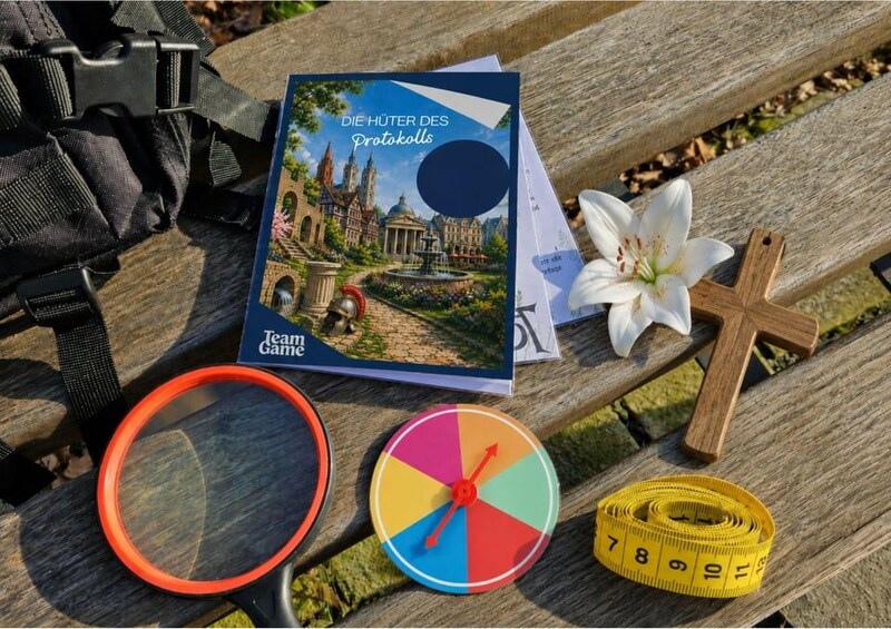 A book titled 'DIE HÜTER DES Protokolls' on a wooden bench, a white flower, a wooden cross, a measuring tape, and a colorful spinner. 2