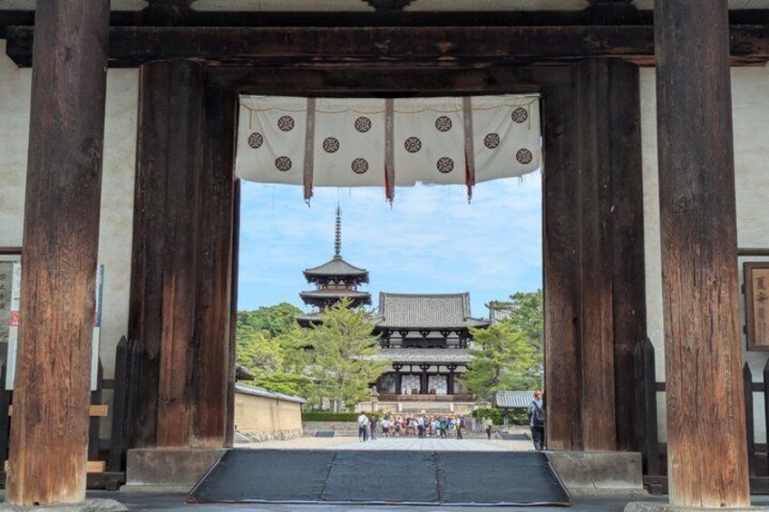 A traditional Japanese gate with a pagoda in the background. 1