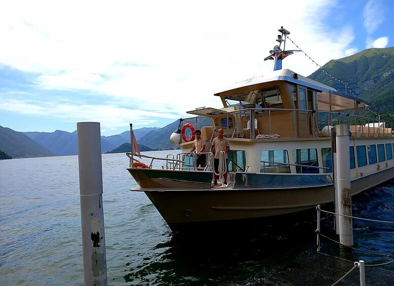 A boat docked at a pier with mountains in the background. 2