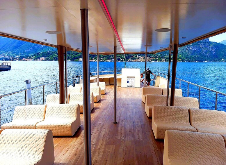 A boat deck with seating and a view of a lake with mountains in the background. 1