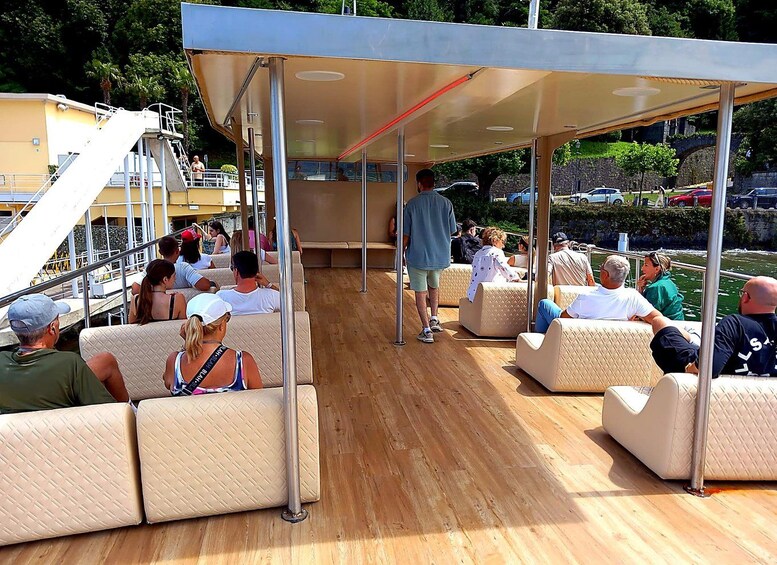 A boat deck with people seated on cushioned benches, a covered area, and a staircase leading to a lower deck. 4