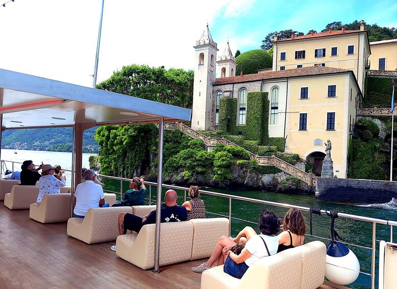 People relaxing on a boat deck with a view of historic buildings and a river. 5
