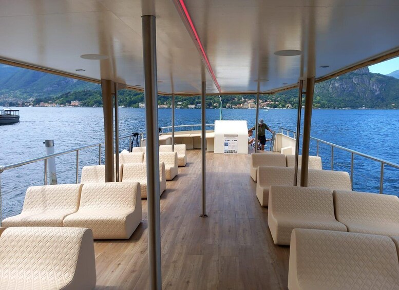 A boat deck with seating and a view of a lake with mountains in the background. 2