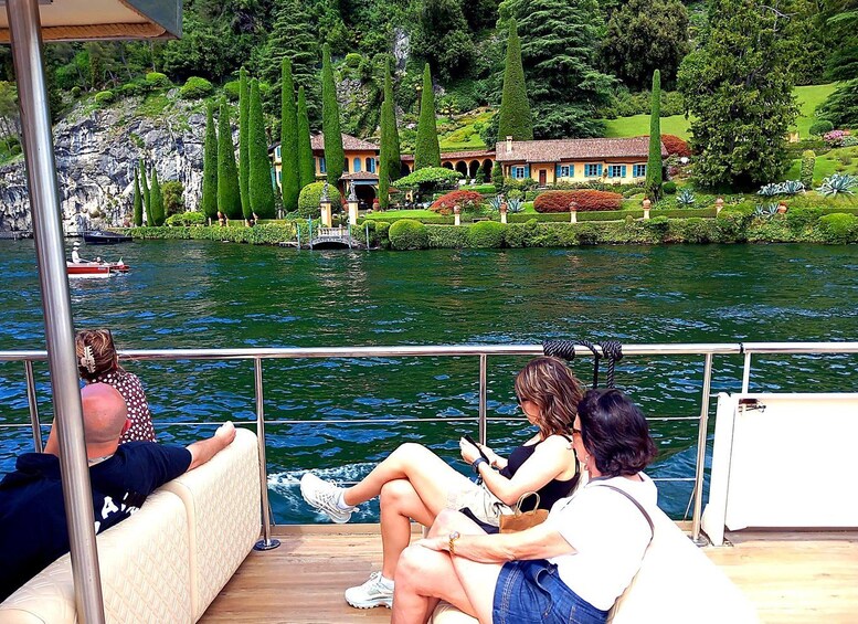 A boat with passengers enjoying the view of a lake, surrounded by lush greenery and a distant building. 3
