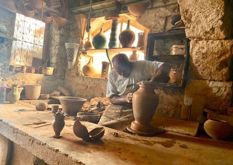 A pottery workshop with a man shaping clay vases on a workbench. 5
