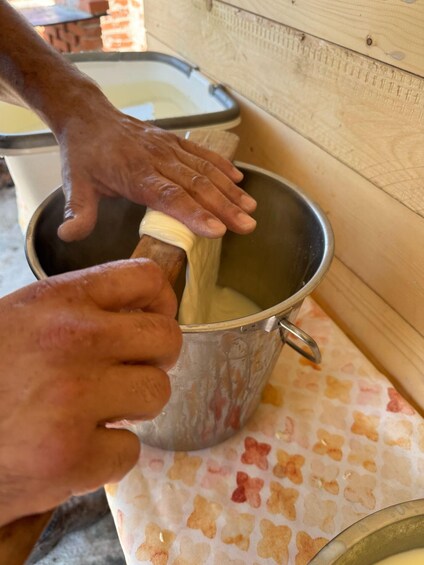 A person kneading dough in a metal bowl. 2