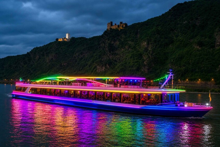 A brightly lit riverboat with a castle in the background. 1