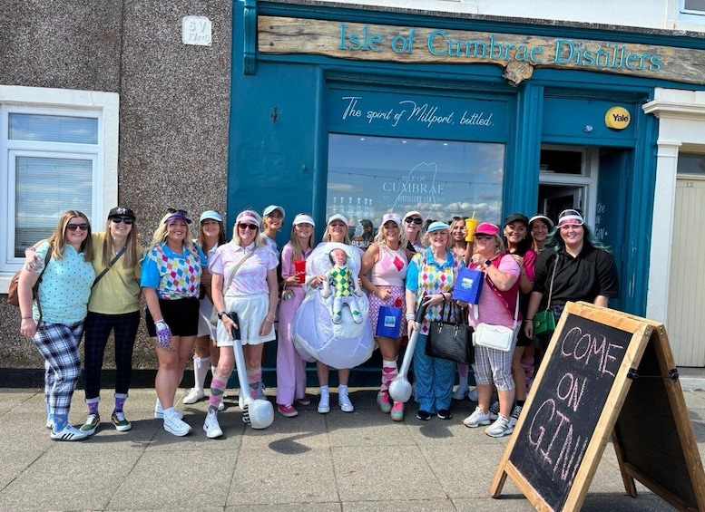 A group of people in front of a distillery with a sign that reads 'Isle of Cumbrae Distillers.' 2