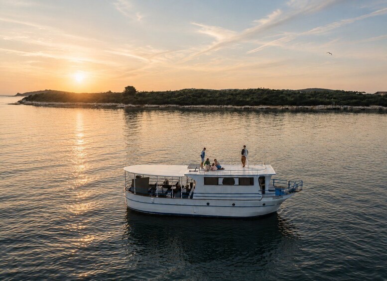 A boat with people on a calm body of water during sunset. 1
