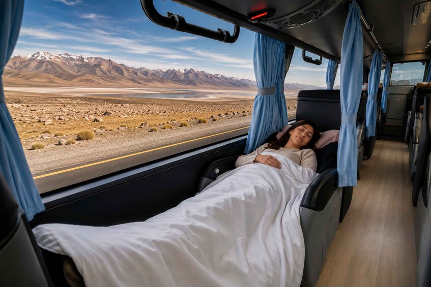A person lying in a bed inside a vehicle with a mountainous landscape visible through the window. 1