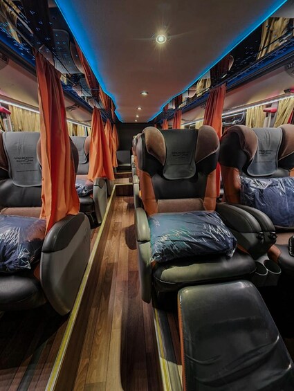 A train carriage interior with leather seats, orange curtains, and wooden flooring. 3