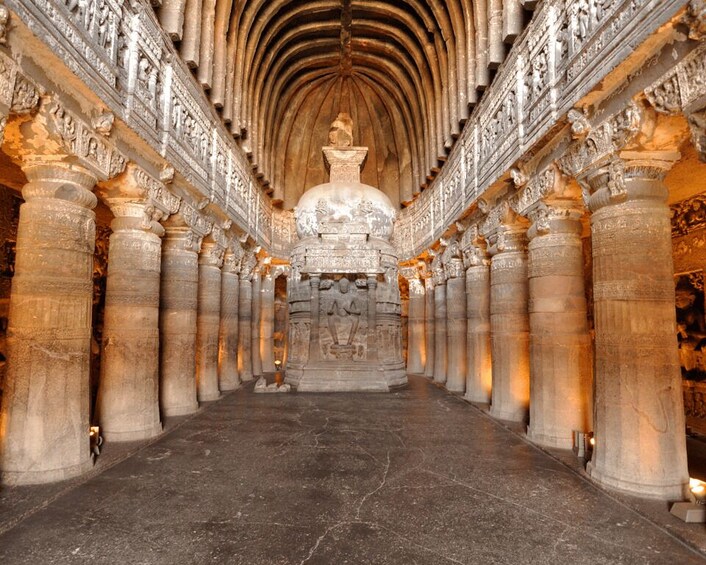 An interior of a temple with a central statue, flanked by ornate columns and detailed carvings. 2