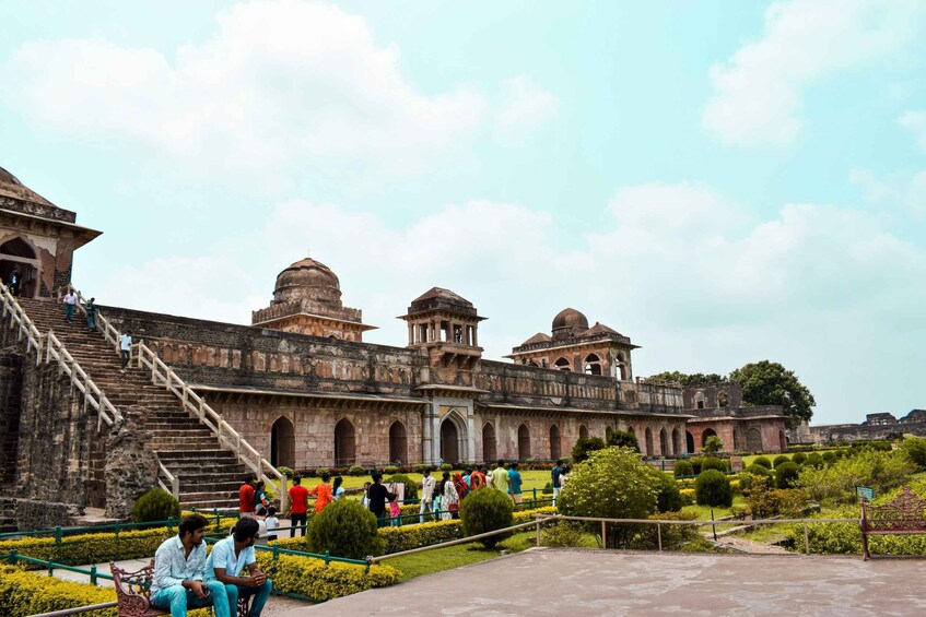 A historic building with arched windows and domed structures, surrounded by a well-maintained garden and a staircase leading up to the entrance. 3