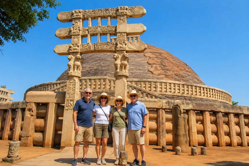 A group of people standing in front of a large, ornate stone structure with a dome and intricate carvings. 1