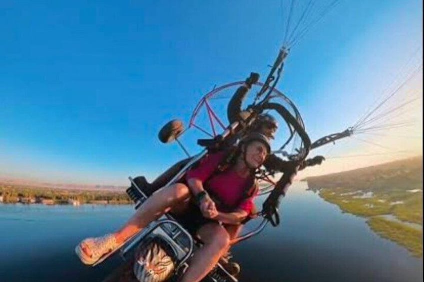 A person on a tandem paragliding flight over a body of water. 4
