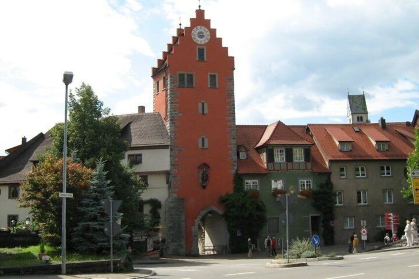 A historic tower with a clock, surrounded by traditional buildings and a clear sky. 3