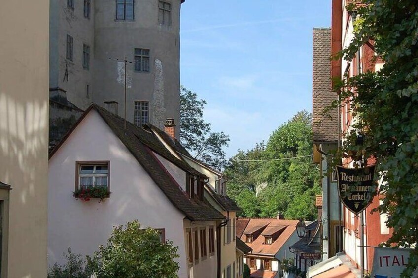 A narrow street with traditional buildings, a sign for a restaurant, and a building with 'ITAL' partially visible. 5