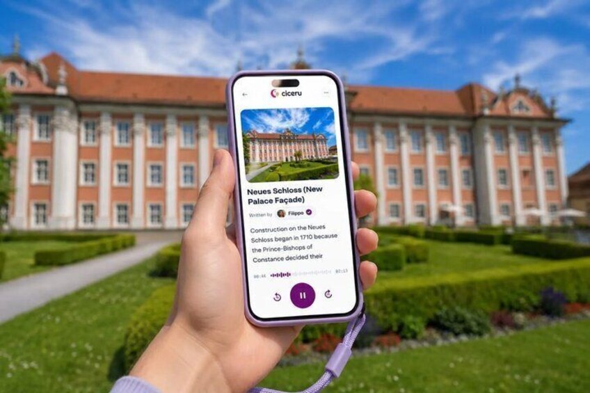 A hand holding a smartphone displaying a photo of a grand building with a caption. 1