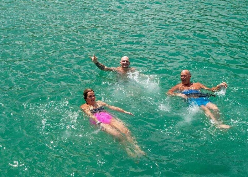 Three people swimming in clear blue water. 2