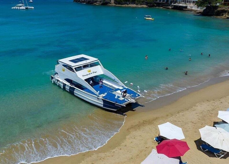 A boat docked at a beach with clear turquoise water and people swimming. 3
