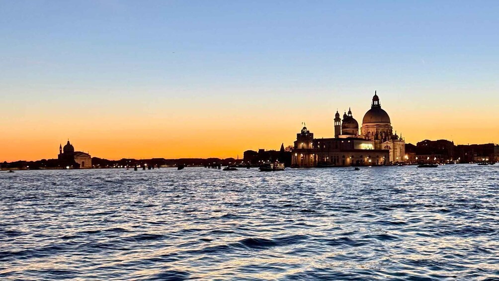 A sunset over a body of water with a prominent domed building and other historical architecture. 2