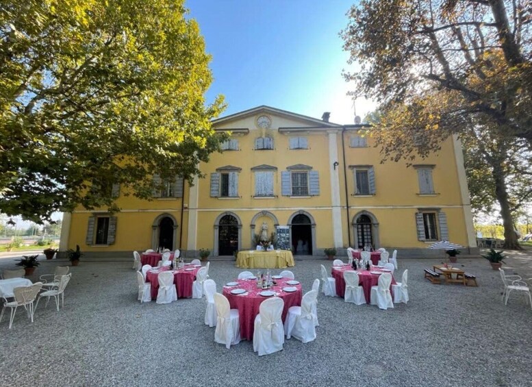 A yellow building with arched doorways, surrounded by tables set for an event. 4