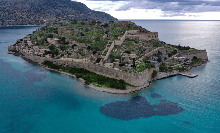 An aerial view of a fortified island with ancient ruins and a clear blue sea. 2