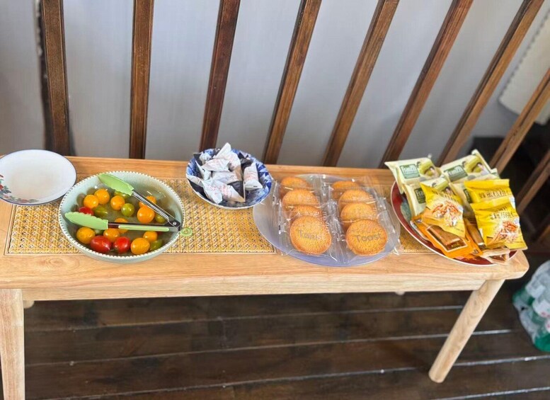 A wooden table with a bowl of cherry tomatoes, a bowl of wrapped snacks, and a plate of cookies. 5