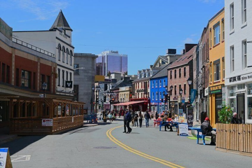 A street with buildings, a pedestrian crossing, and a clear sky. 2